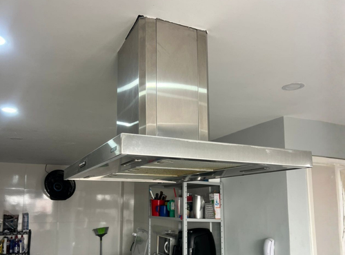 Técnico instalando coifa de aço inox acima do cooktop