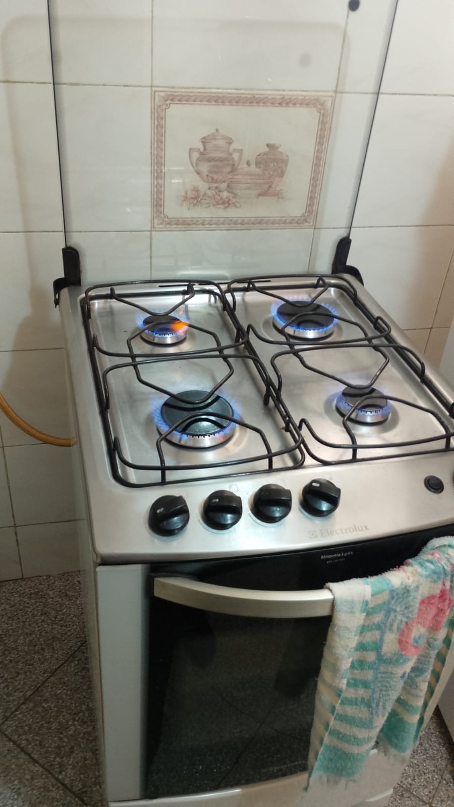 Técnico ajustando o injetor do queimador de um fogão durante conversão de gás